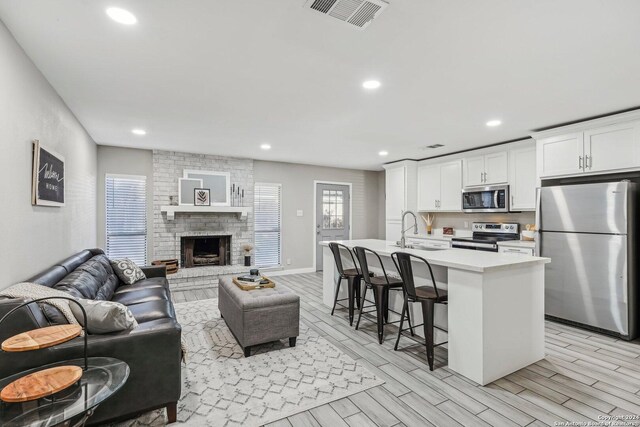 4911 Dare, San Antonio, TX 78217 - kitchen featuring white cabinets, light wood-type flooring, stainless steel appliances, and a kitchen island with sink
