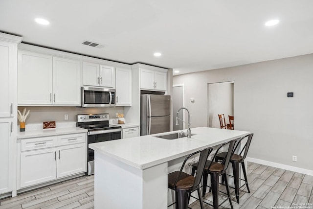 4911 Dare, San Antonio, TX 78217 - kitchen featuring appliances with stainless steel finishes, a breakfast bar, sink, white cabinetry, and an island with sink