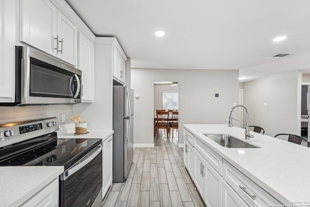 4911 Dare, San Antonio, TX 78217 - kitchen featuring sink, stainless steel appliances, light stone counters, light hardwood / wood-style flooring, and white cabinets