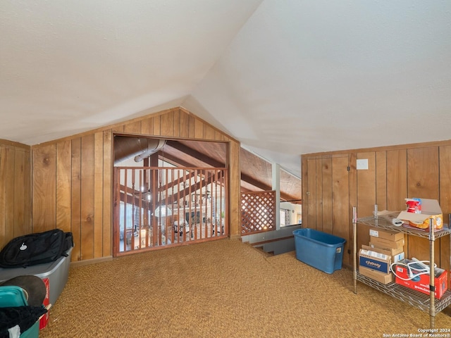 additional living space with carpet, lofted ceiling, and wooden walls