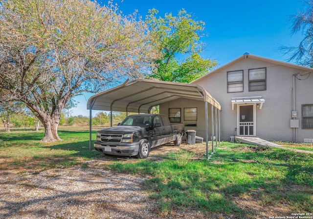 view of parking / parking lot with a carport and a yard