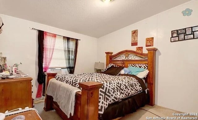 bedroom with a textured ceiling, lofted ceiling, and light carpet