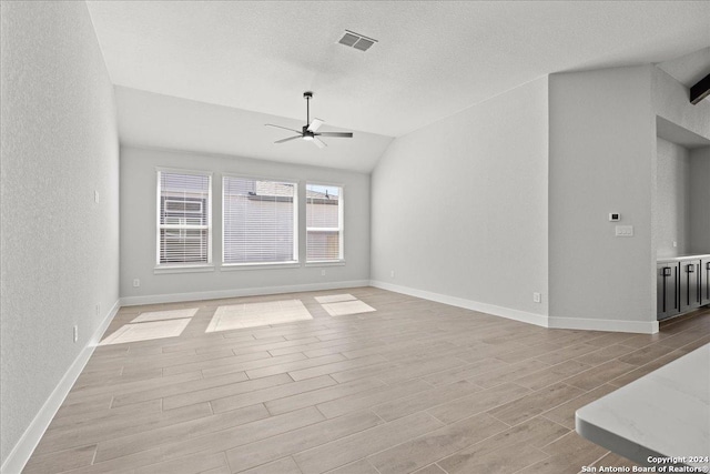 unfurnished living room with a textured ceiling, ceiling fan, lofted ceiling, and light wood-type flooring