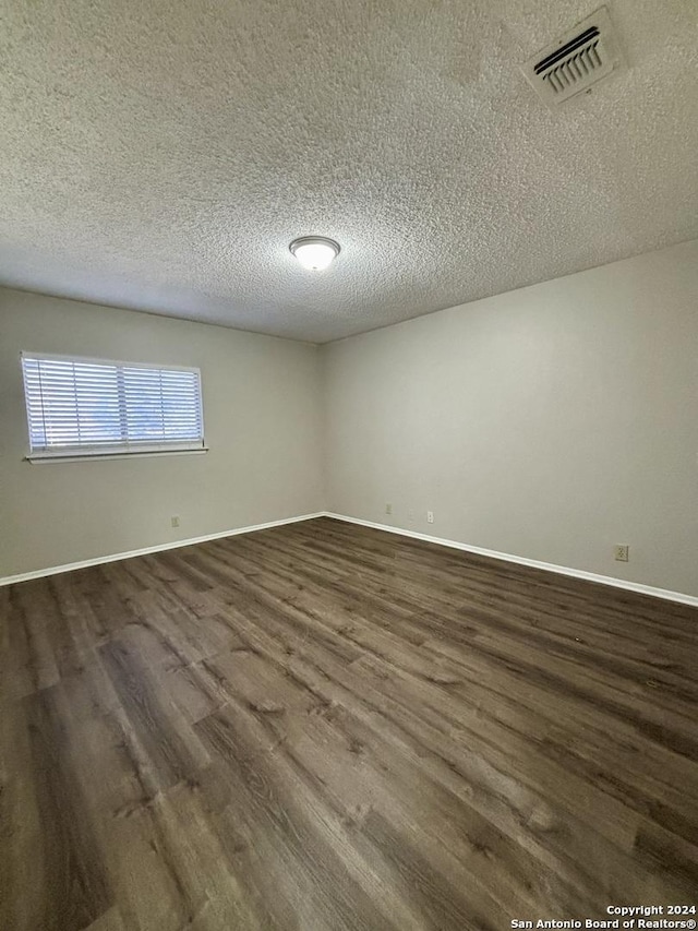 spare room with a textured ceiling and dark wood-type flooring