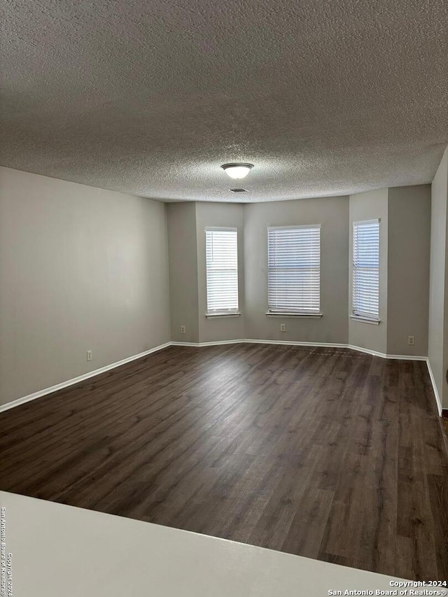 unfurnished room with dark hardwood / wood-style flooring and a textured ceiling