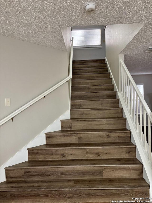 staircase featuring wood-type flooring and a textured ceiling