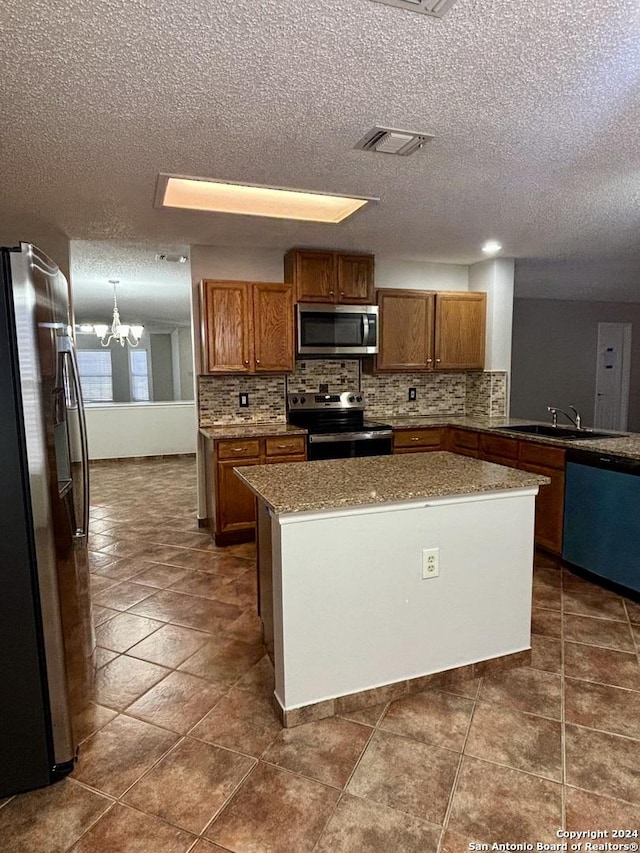 kitchen featuring an inviting chandelier, sink, decorative backsplash, a textured ceiling, and appliances with stainless steel finishes