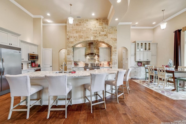 kitchen with a large island with sink, high quality appliances, dark hardwood / wood-style flooring, and decorative light fixtures