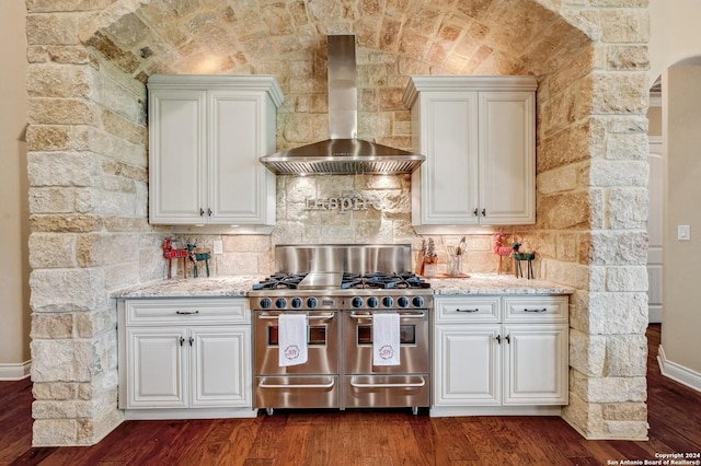 kitchen featuring backsplash, wall chimney exhaust hood, dark wood-type flooring, and range with two ovens