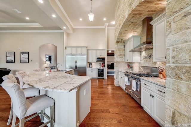 kitchen featuring white cabinets, dark hardwood / wood-style floors, high quality appliances, and wall chimney range hood