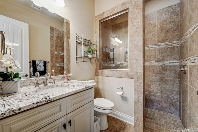 bathroom featuring a tile shower, tile patterned flooring, vanity, and toilet