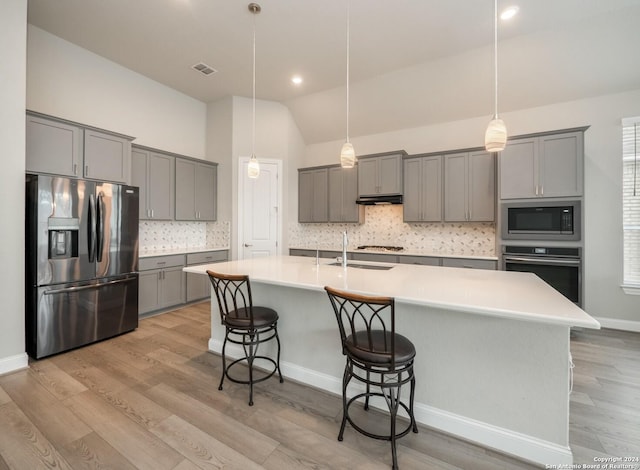 kitchen featuring gray cabinetry, light wood-type flooring, lofted ceiling, and appliances with stainless steel finishes