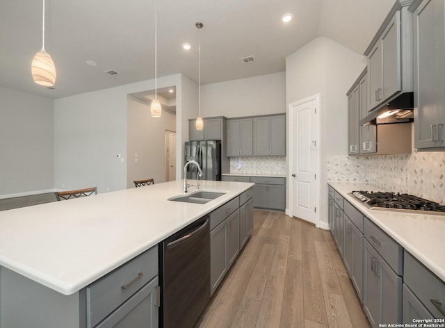 kitchen with gray cabinetry, sink, pendant lighting, appliances with stainless steel finishes, and light wood-type flooring