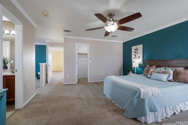 bedroom with ensuite bath, ornamental molding, light colored carpet, ceiling fan, and a spacious closet