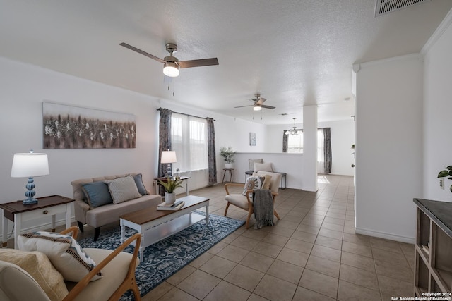 living room with ceiling fan with notable chandelier, light tile patterned floors, and a textured ceiling