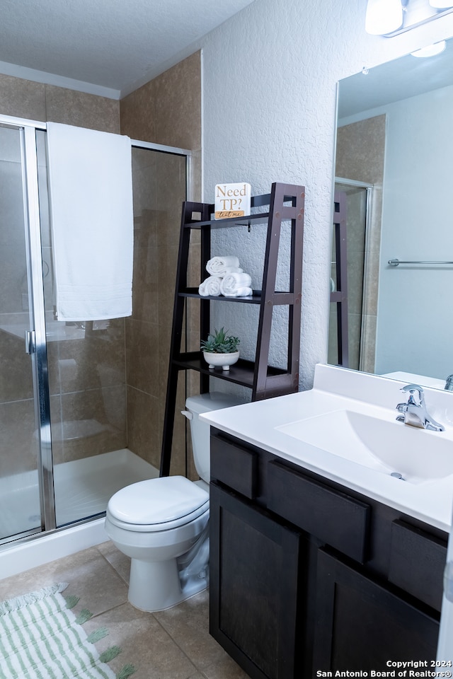 bathroom featuring tile patterned floors, vanity, a shower with shower door, and toilet