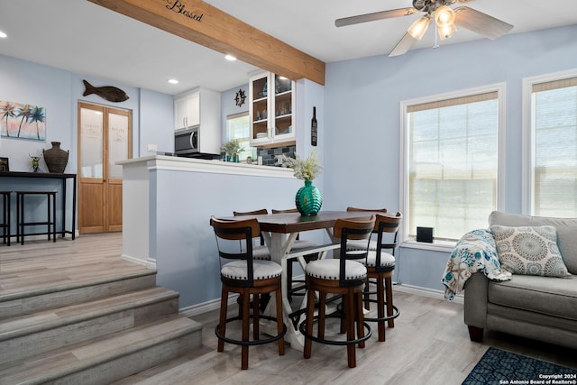 dining space with plenty of natural light, light hardwood / wood-style floors, beam ceiling, and ceiling fan