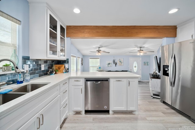 kitchen featuring backsplash, kitchen peninsula, light hardwood / wood-style flooring, white cabinetry, and stainless steel appliances