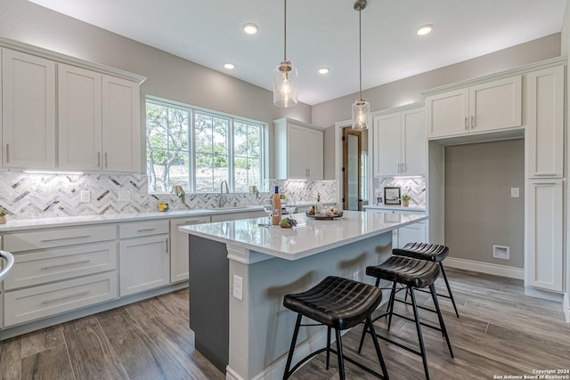 kitchen featuring white cabinets, a center island, pendant lighting, and hardwood / wood-style floors