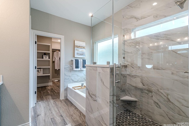 bathroom with wood-type flooring and shower with separate bathtub