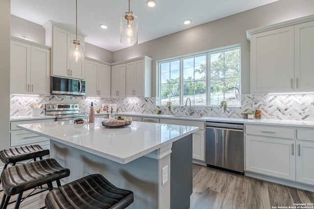 kitchen featuring sink, white cabinetry, hanging light fixtures, and appliances with stainless steel finishes