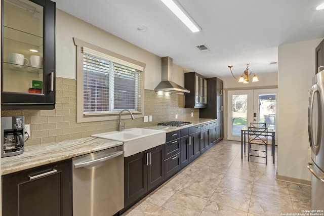 kitchen featuring appliances with stainless steel finishes, wall chimney exhaust hood, sink, a chandelier, and hanging light fixtures