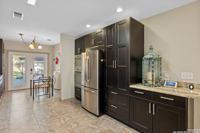 kitchen featuring light stone countertops, french doors, a chandelier, washer / dryer, and appliances with stainless steel finishes