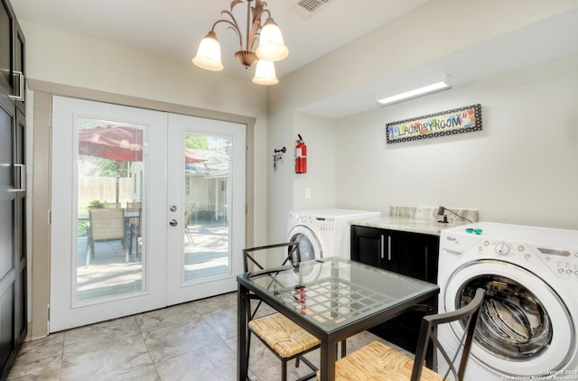 clothes washing area featuring washer and clothes dryer, a notable chandelier, and french doors