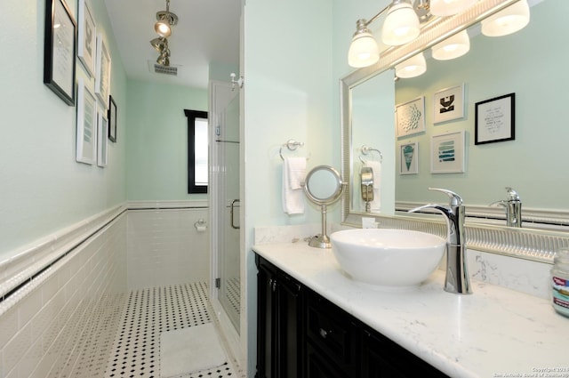 bathroom featuring vanity, tile walls, and a shower with shower door