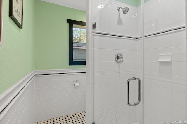 bathroom with tile walls and a shower with shower door