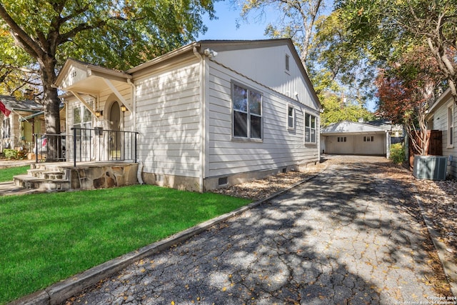 view of side of property featuring a yard, central AC, a garage, and an outdoor structure