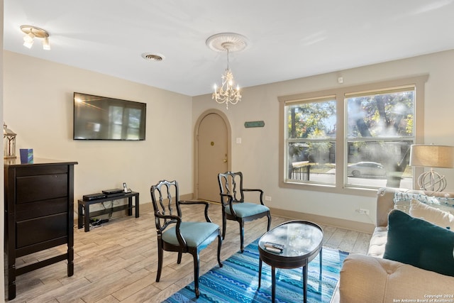 living area with an inviting chandelier and light hardwood / wood-style flooring