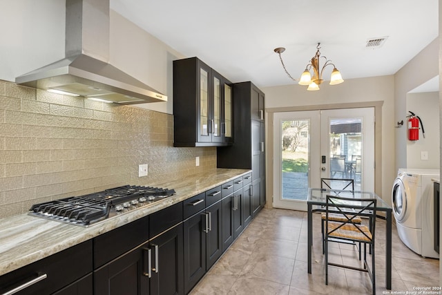 kitchen with wall chimney exhaust hood, light stone countertops, separate washer and dryer, and stainless steel gas cooktop