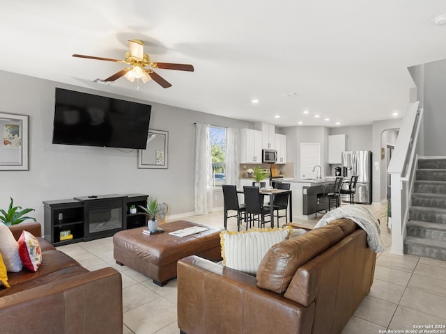 tiled living room featuring a fireplace, ceiling fan, and sink