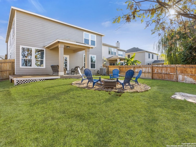 rear view of property featuring a lawn, central AC unit, a deck, and an outdoor fire pit