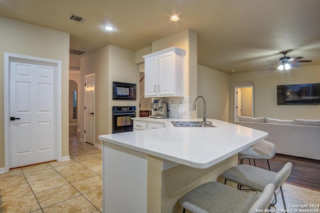 kitchen with ceiling fan, sink, a kitchen breakfast bar, kitchen peninsula, and black appliances