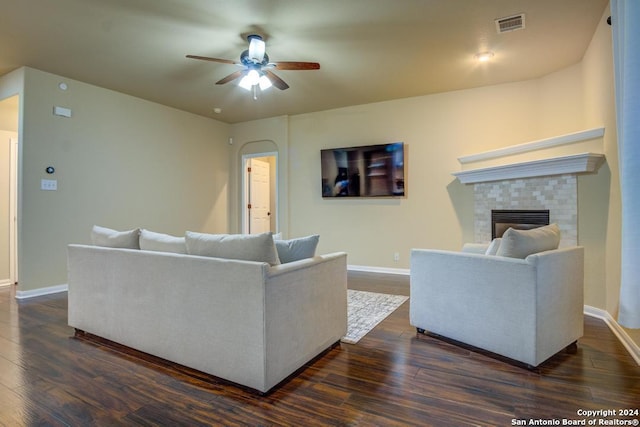 living room featuring a tiled fireplace, ceiling fan, and dark hardwood / wood-style flooring