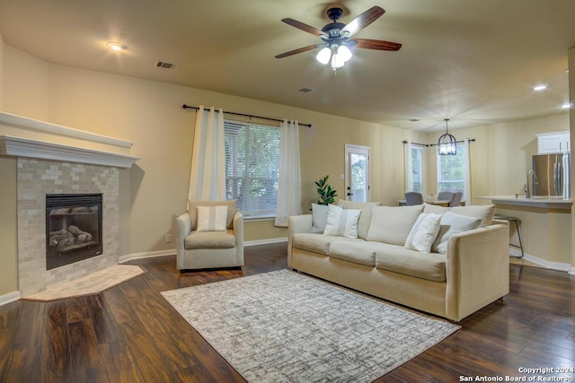 living room featuring ceiling fan with notable chandelier, dark hardwood / wood-style flooring, and a fireplace