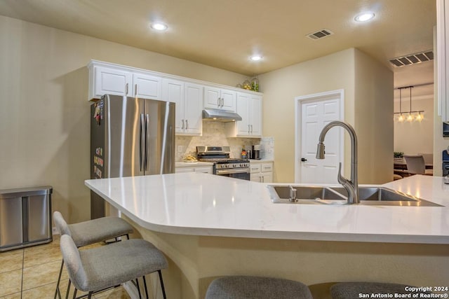 kitchen featuring pendant lighting, backsplash, white cabinets, sink, and appliances with stainless steel finishes