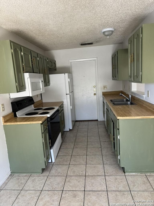 kitchen with white appliances, sink, green cabinetry, light tile patterned floors, and a textured ceiling