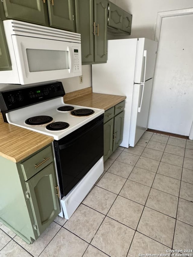 kitchen with green cabinets, white appliances, and light tile patterned floors