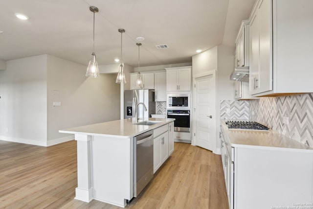 kitchen featuring sink, hanging light fixtures, an island with sink, stainless steel appliances, and white cabinets