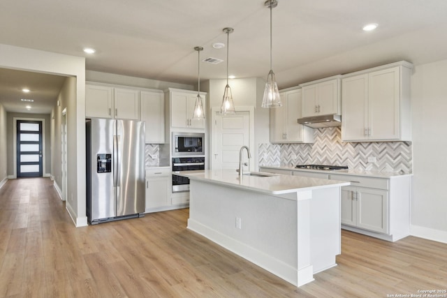 kitchen with sink, appliances with stainless steel finishes, white cabinetry, a kitchen island with sink, and light wood-type flooring