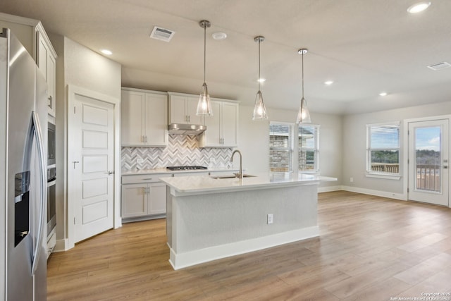 kitchen featuring stainless steel appliances, sink, a center island with sink, and white cabinets