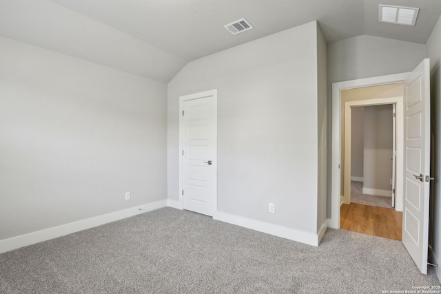 unfurnished bedroom featuring light carpet and vaulted ceiling