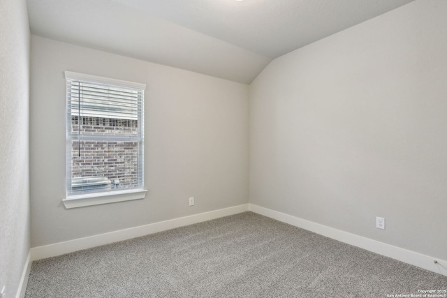 empty room featuring vaulted ceiling and carpet flooring