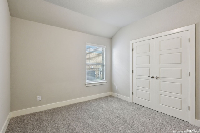 unfurnished bedroom with lofted ceiling, light colored carpet, and a closet