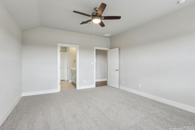 unfurnished bedroom featuring lofted ceiling, ensuite bath, light colored carpet, and ceiling fan