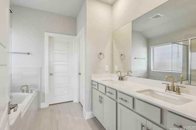 bathroom with vanity and tiled bath