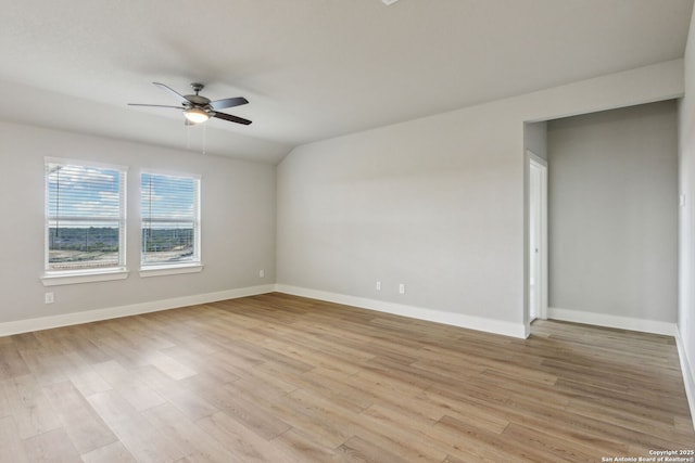 empty room with ceiling fan, vaulted ceiling, and light hardwood / wood-style flooring